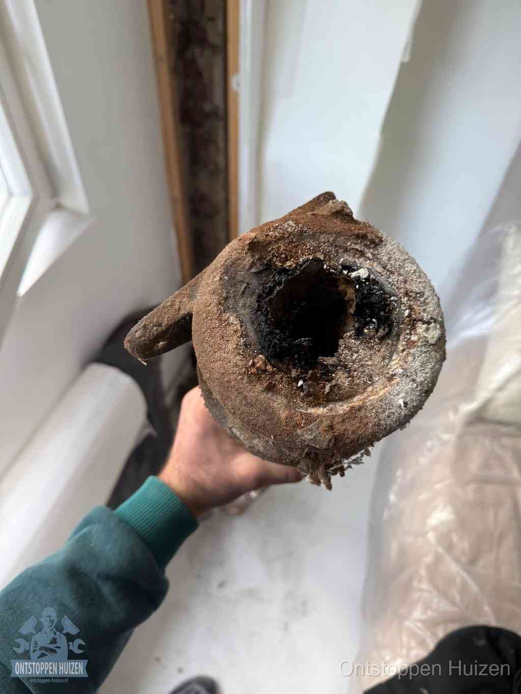 Een doorgezaagd stuk afvoerbuis dat vrijwel volledig is dichtgekoekt, het gevolg van een gootsteenverstopping te lang laten zitten in Huizen