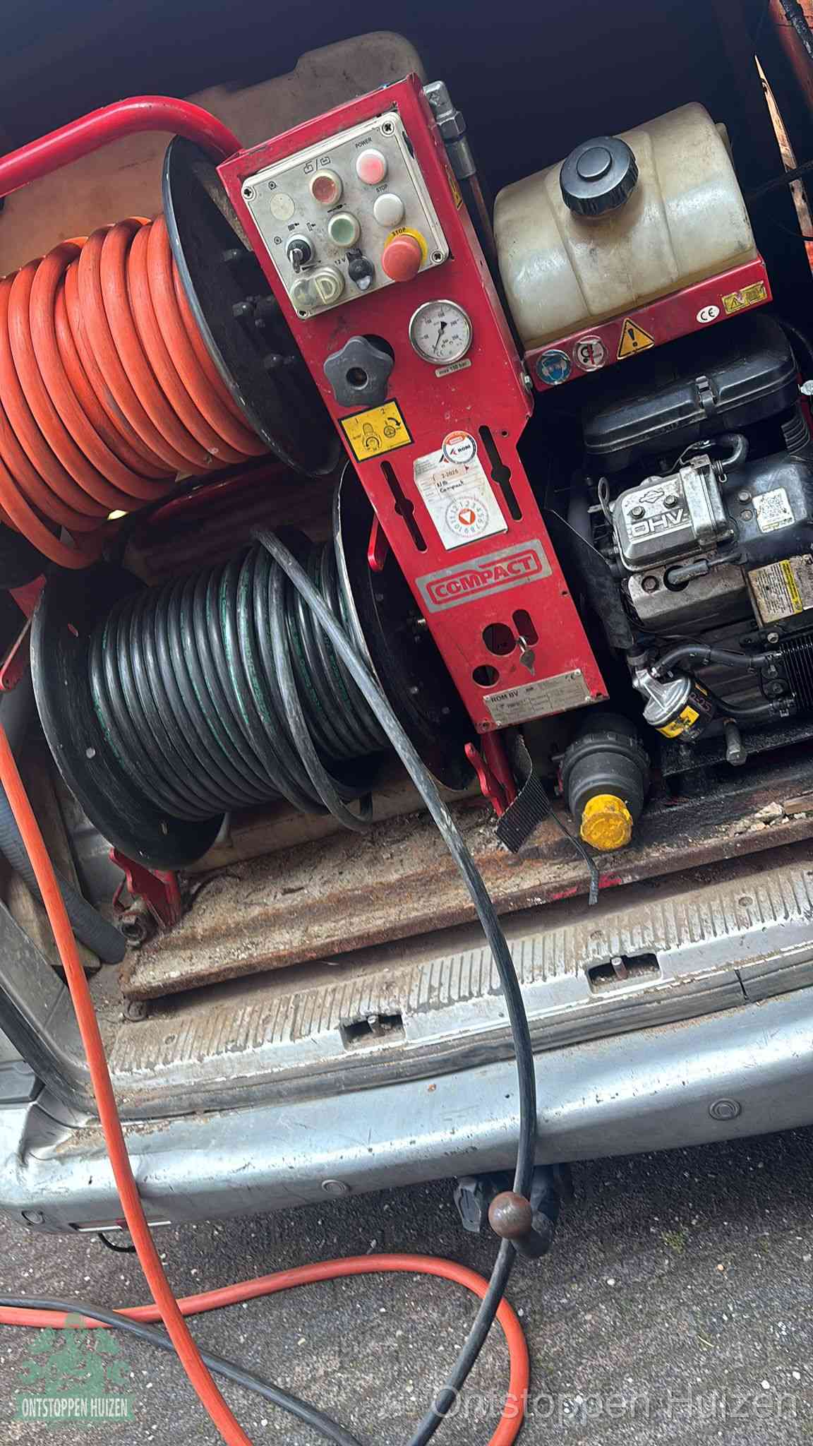 Een rood hogedruk-rioolreinigingstoestel in de laadbak van de bedrijfsbus, apparatuur voor een hardnekkige afvoerverstopping in Huizen