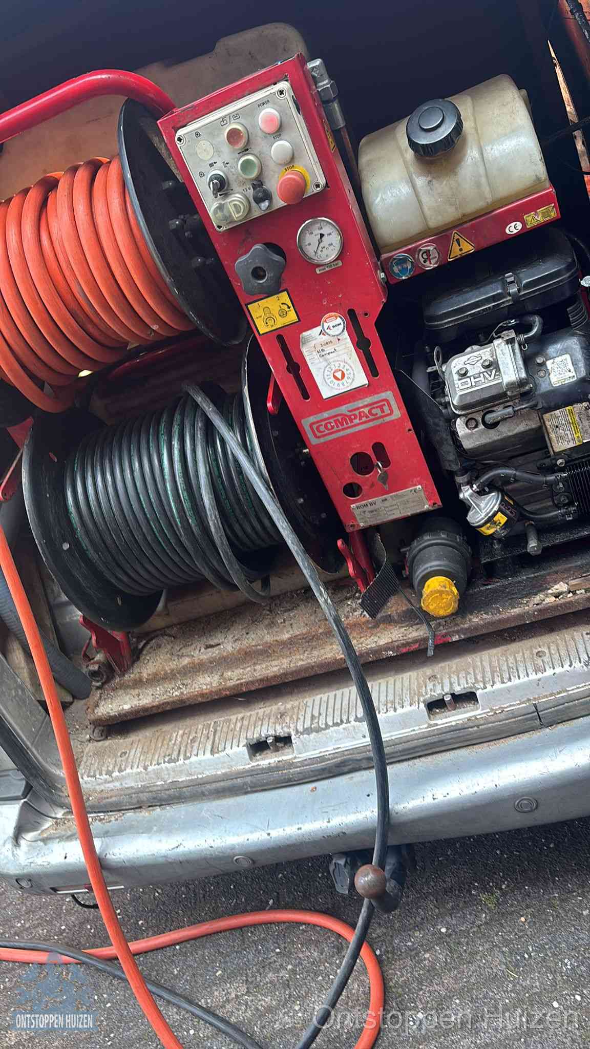 Een rood hogedruk-rioolreinigingstoestel met slangen in de laadbak van de bedrijfsbus, apparatuur voor een hardnekkige wc-verstopping in Huizen