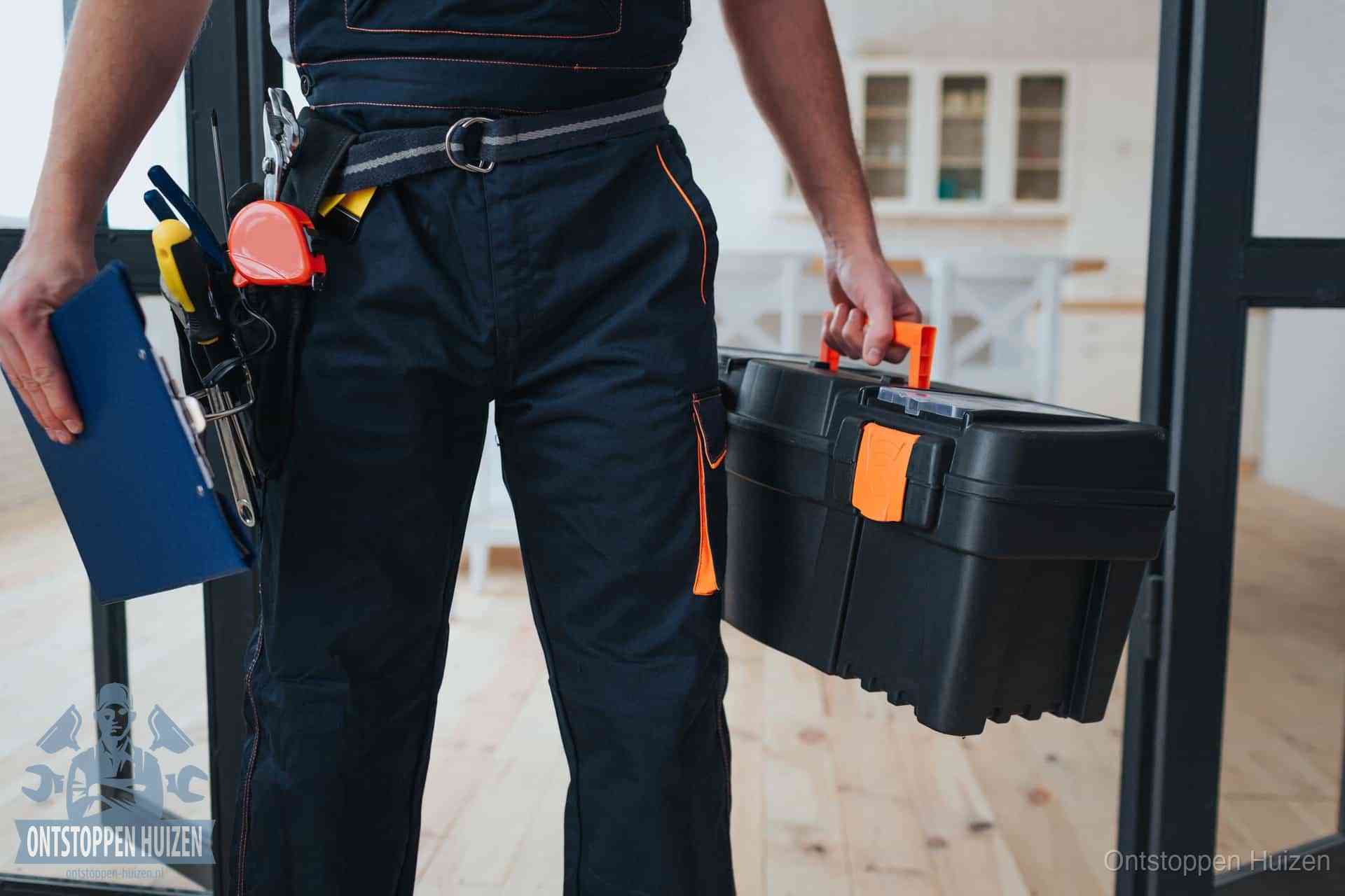 Een monteur met gereedschapsriem en klembord in een keuken, klaar om een transparante prijs voor het gootsteen ontstoppen in Huizen te geven
