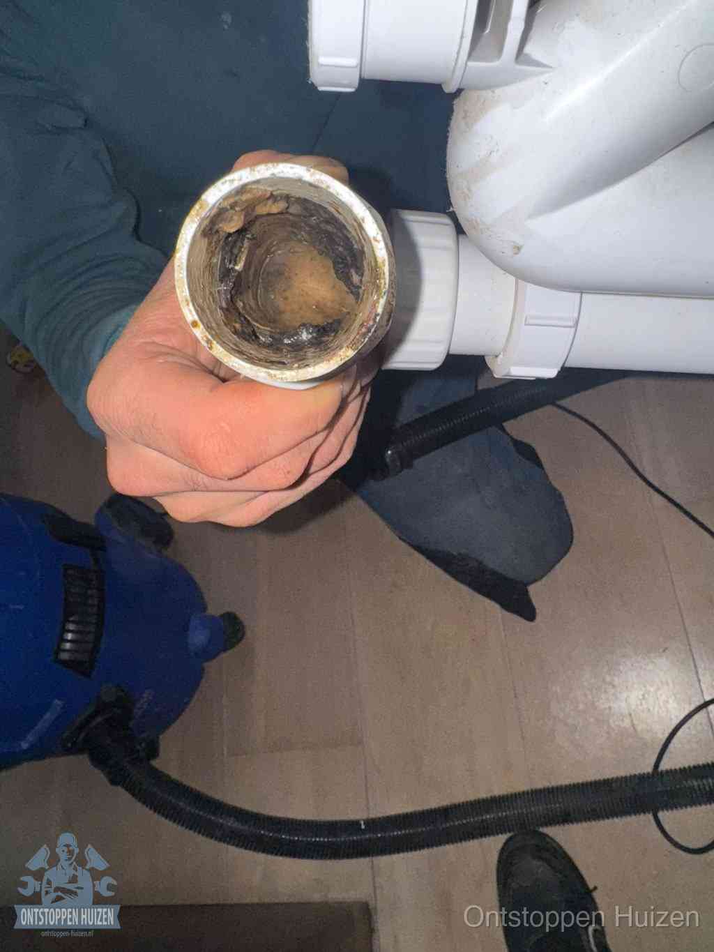 Een losgekoppelde afvoerbuis die van binnen volledig is dichtgeslibd met vet en aanslag, de meest voorkomende oorzaak van een verstopte gootsteen in Huizen