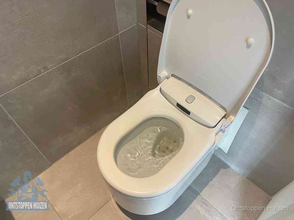 Een toiletpot vol troebel water met drijvend papier en restanten, de meest voorkomende oorzaak van een verstopte wc in Huizen