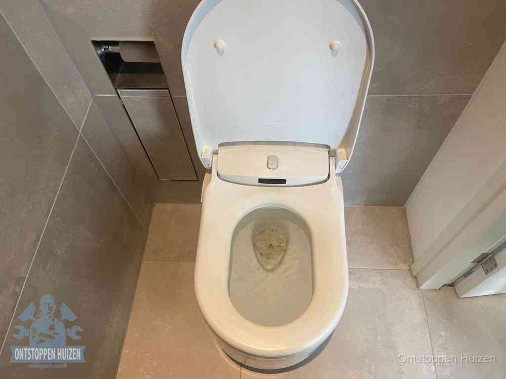 Een wit hangtoilet waarin een prop wc-papier op het water blijft drijven, een duidelijk signaal van een verstopte wc in Huizen
